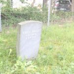 Grabstein vor Zaun Friedhof Schönow